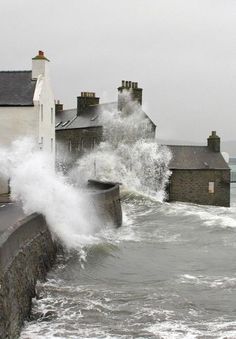 waves crashing against the sea wall and houses