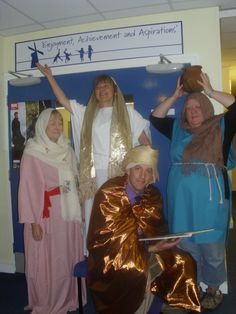 four people dressed up in costumes posing for the camera with their arms raised above their heads