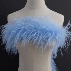 a white mannequin with blue feathers on it