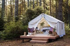 a white tent sitting in the middle of a forest