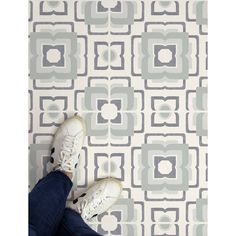 someone is standing on the floor in front of a wallpaper with grey and white squares