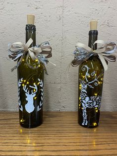 two wine bottles decorated with lights and bows