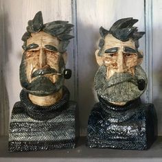 two ceramic busturines of men with beards and moustaches on their faces