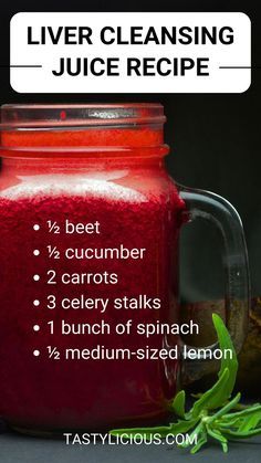 a jar filled with red liquid next to some green leaves and a lemon on the side