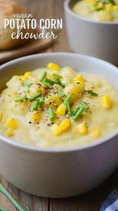 two white bowls filled with corn soup on top of a wooden table next to bread