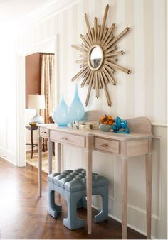 a wooden table topped with a blue vase and mirror