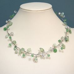 This necklace is made from a mixture of glass, imitation pearl, Czech glass, and glass leaf beads.  Strung and twisted on silvery wire, they resemble leaves on a branch.  This necklace is very light and comfortable to wear (despite its looks), and can be bent into whatever shape you like.  Being more three dimensional than many necklaces also adds interest.  This necklace is 18.5 inches long, with a lobster-claw clasp.  The length can be altered upon request.  It will be flattened somewhat for s Cheap Green Beaded Pearl Necklace, Affordable Green Elegant Pearl Necklace, Cheap Green Glass Beaded Necklaces, Czech Glass Necklace, Leaf Beads, Branch Necklace, Green Beaded Necklace, Peridot Green, Leaf Necklace