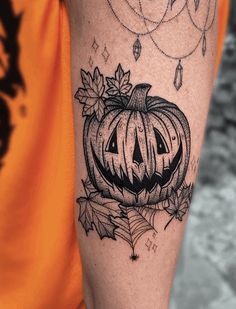 a black and white photo of a pumpkin with leaves on it's arm, in front of an orange t - shirt