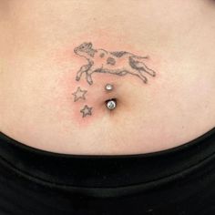 a woman's stomach with a small tattoo on the side of her belly that has stars and a dog