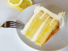 a slice of cake on a plate with a fork next to it and lemons in the background