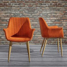 two orange chairs sitting next to each other in front of a brick wall and floor