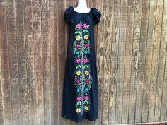 An ethnic, festive dress that is embellished with floral embroidery. No stretch at neckline.  Size large. Good condition.  Measurements taken across front laid flat Bust21" Shoulder to hem59" Waist20" Black Embroidered Neckline Fitted Dress, Black Embroidered Dress With Fitted Neckline, Black Fitted Embroidered Dress For Festival, Fitted Black Dress With Embroidered Neckline, Fitted Folk Style Festival Dress, Fitted Folk Style Dress For Festival, Fitted Black Dress For Festivals, Fitted Dress With Multicolor Embroidery For Festival, Black Floral Embroidered Dress For Festival