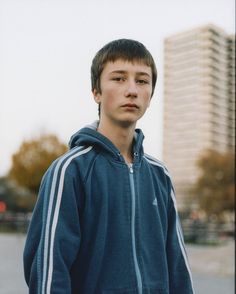 a young man standing in front of tall buildings