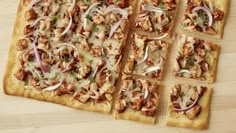 several square pizzas with onions and meat toppings on a wooden surface, ready to be eaten