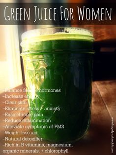 a jar filled with green juice sitting on top of a wooden table