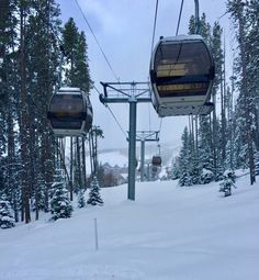 a ski lift with two people on it in the middle of snow covered ground and trees