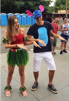 two people dressed in costumes standing next to each other on a sidewalk with one person pointing at the camera