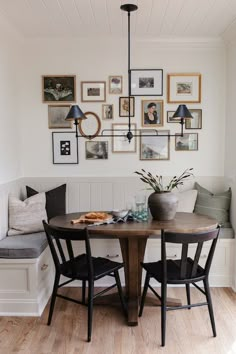 a dining room table with four chairs and pictures on the wall above it, along with a bench