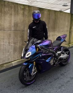 a man standing next to a purple motorcycle