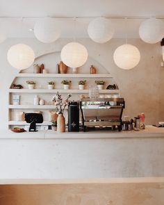 a coffee shop with white lights hanging from the ceiling and shelves on the wall above