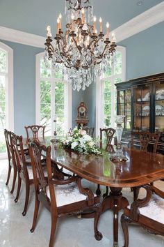 a formal dining room with blue walls and chandelier hanging from the ceiling,