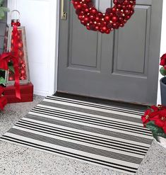 a christmas wreath on the front door with poinsettis and other holiday decorations