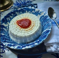 a blue and white plate topped with food on top of a table next to a spoon