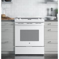 a white stove top oven sitting inside of a kitchen next to counter tops and drawers