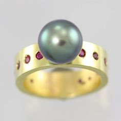 Very contemporary and classy Tahitian Pearl and Gold Ring with Rubies. This piece is crafted by hand in Hawaii by Laine Benthall. The ring shank is 14k yellow gold with 14 high quality round faceted ruby stones. There are two 2mm Rubies and twelve 1.75mm Rubies flush set around the ring shank. An A grade 9mm Tahitian Pearl is attached to the ring. Ring is a size 6.5 This item can be made in any ring size and with any stone. Please ask for a price quote. Ring shank is 6mm wide and 2mm thick. Come Birthstone Jewelry Mothers, Ring With Stone, Pearl Drop Pendant, Family Rings, Mother Rings, Stone Wrapping, Ruby Stone, Tahitian Pearls, Honolulu