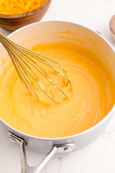 a whisk in a pan with some yellow liquid on the side next to other ingredients