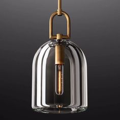 a glass and brass pendant light hanging from a ceiling fixture on a black wall background