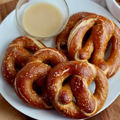 some pretzels are on a white plate next to a glass of milk