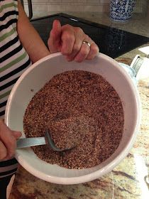 a woman is holding a bowl full of brown stuff with a large spoon in it