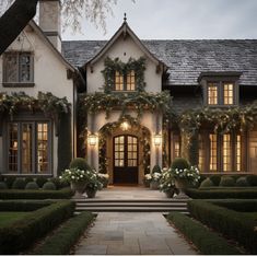 a large house with lots of windows and plants on the front door, surrounded by hedges