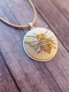 a close up of a necklace on a wooden surface with a beaded bee design