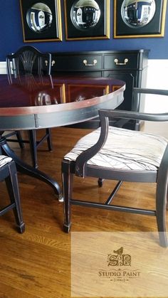 a dining room table with two chairs next to it and pictures on the wall behind it