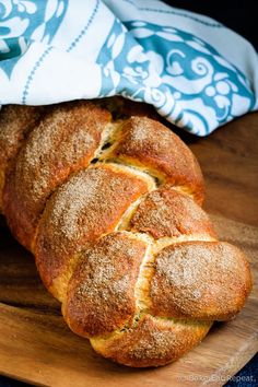 a loaf of bread sitting on top of a wooden cutting board next to a blue and white towel