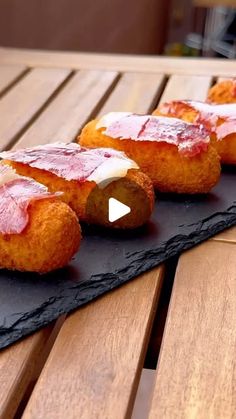 some food is laying out on a black slate plate and sitting on a wooden table