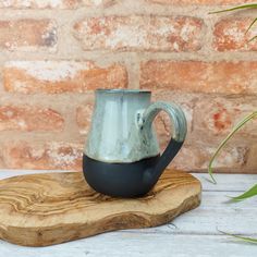 a metal mug sitting on top of a wooden board