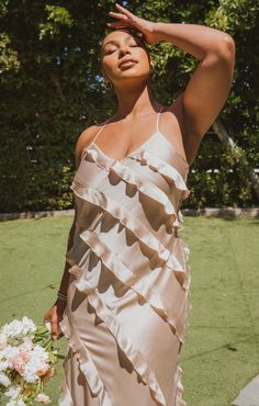 a woman in a dress is holding her hand on her head and posing for the camera