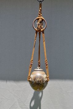 an old fashioned hanging vase on a hook with a chain attached to it's side