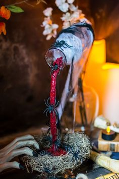 a creepy doll is pouring blood from a bottle into a glass vase with candles in the background