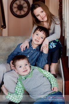 a woman and two boys are sitting on the stairs with their arms around each other