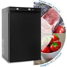 a black refrigerator freezer sitting next to a bowl of strawberries and sliced meat