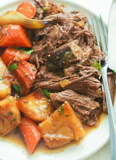 a white plate topped with meat, potatoes and carrots next to a knife and fork