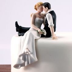 a bride and groom figurine sitting on top of a cake