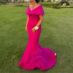 a woman in a bright pink gown standing on the grass