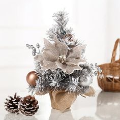 a small christmas tree in a vase with ornaments on it and a pine cone next to it