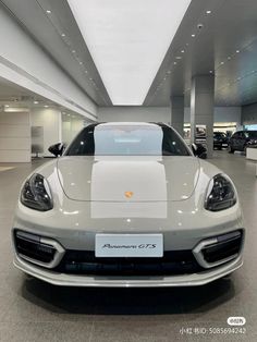 the front end of a silver sports car in a showroom