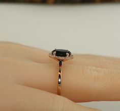 a woman's hand holding a ring with a black stone on it and diamonds around the band